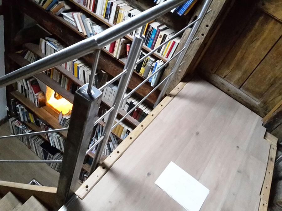 Eine Treppe mit Edelstahlgeländer, die zu einem Bücherregal führt
