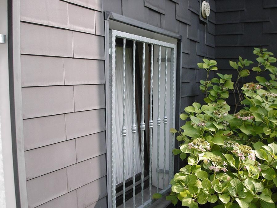 Ein Fenster mit einem Zaun darum und einem Busch davor