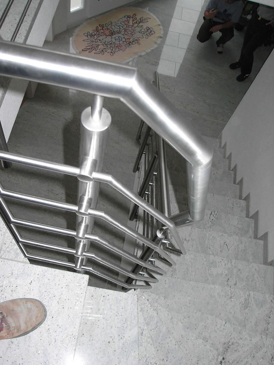 Eine Person steht neben einer Treppe mit einem Edelstahlgeländer.