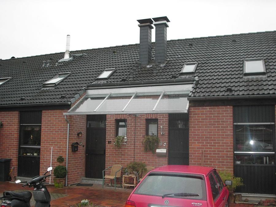 Ein rotes Auto steht vor einem Backsteinhaus