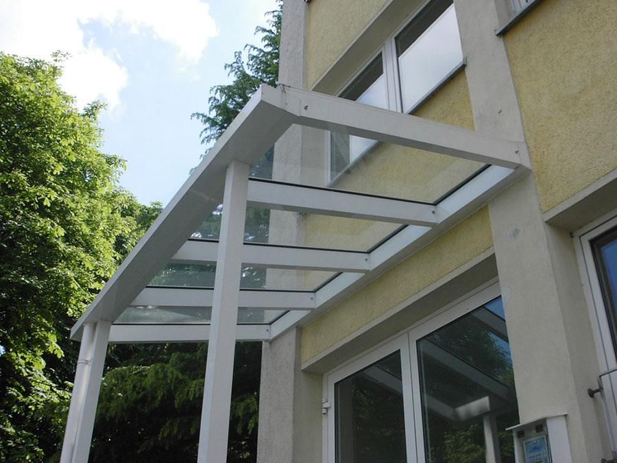 Ein weißes Gebäude mit einem Glasdach über einer Tür