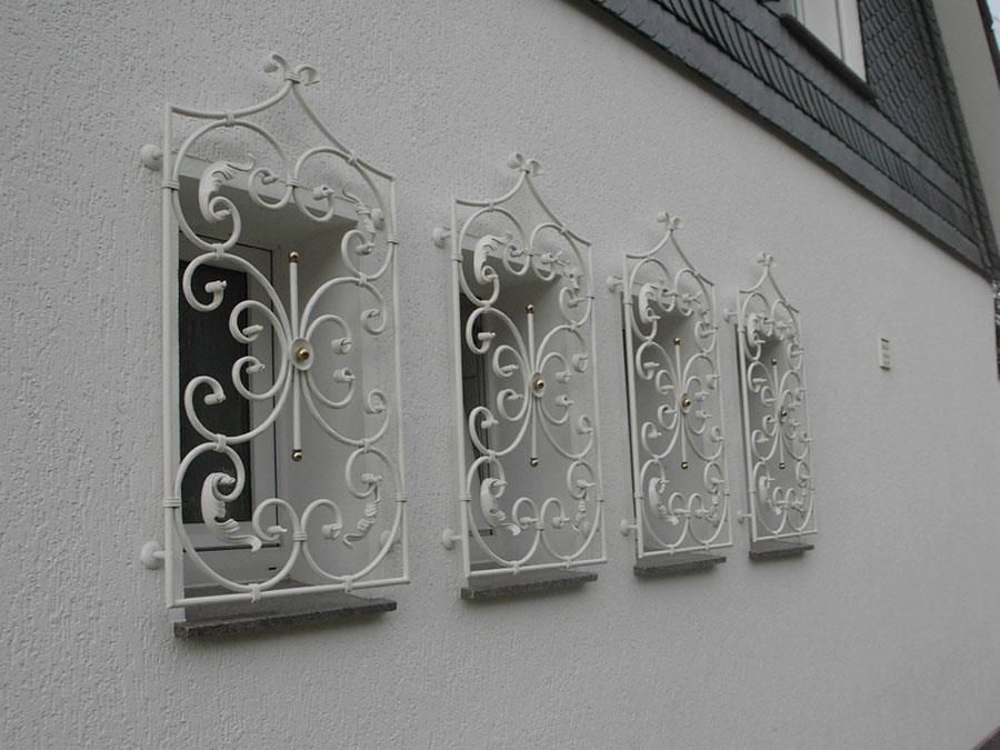 Eine Reihe weißer Fenster mit schmiedeeisernen Gittern