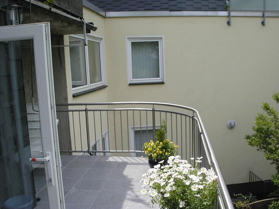 Ein Balkon mit einem Edelstahlgeländer und Blumen darauf