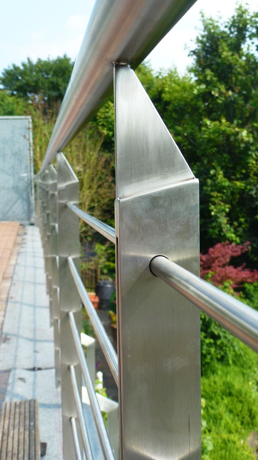 Eine Nahaufnahme eines Edelstahlgeländers mit Bäumen im Hintergrund