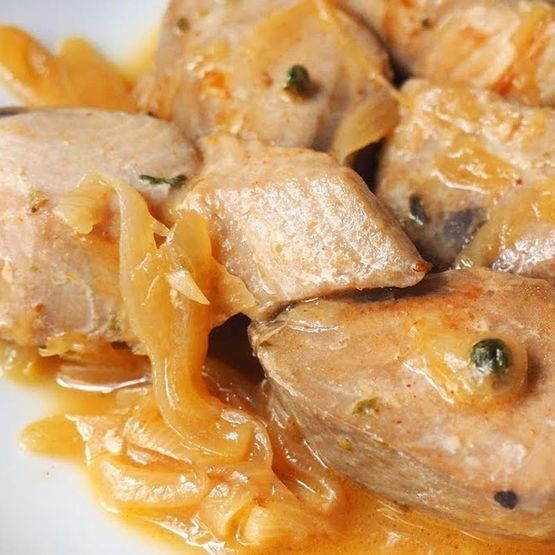 Un primer plano de un plato de comida con carne y cebollas sobre una mesa.