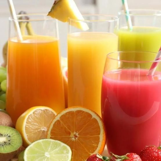 Una variedad de jugos de frutas en vasos con pajitas.