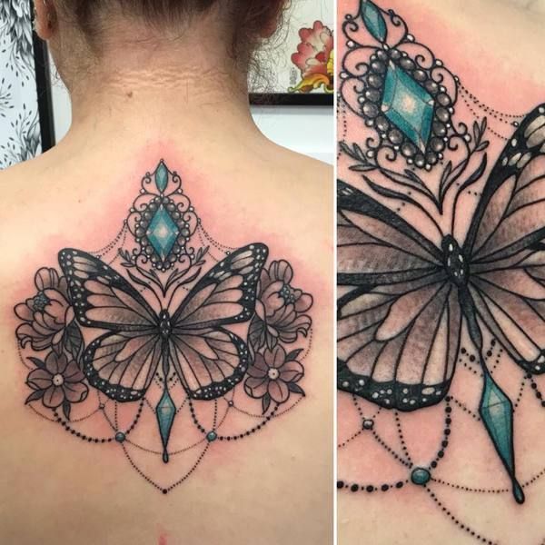 Delphine, tatouage d'un papillon noir avec un cristal bleu