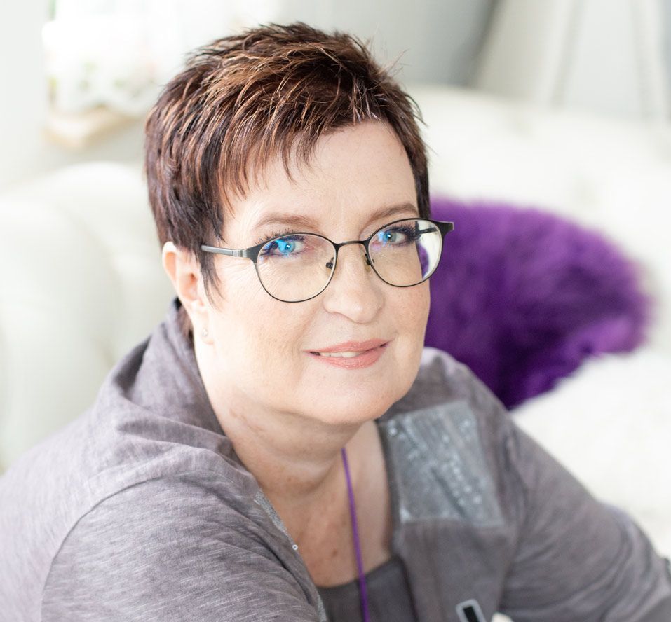 Eine Frau mit Brille und lila Hemd lächelt in die Kamera