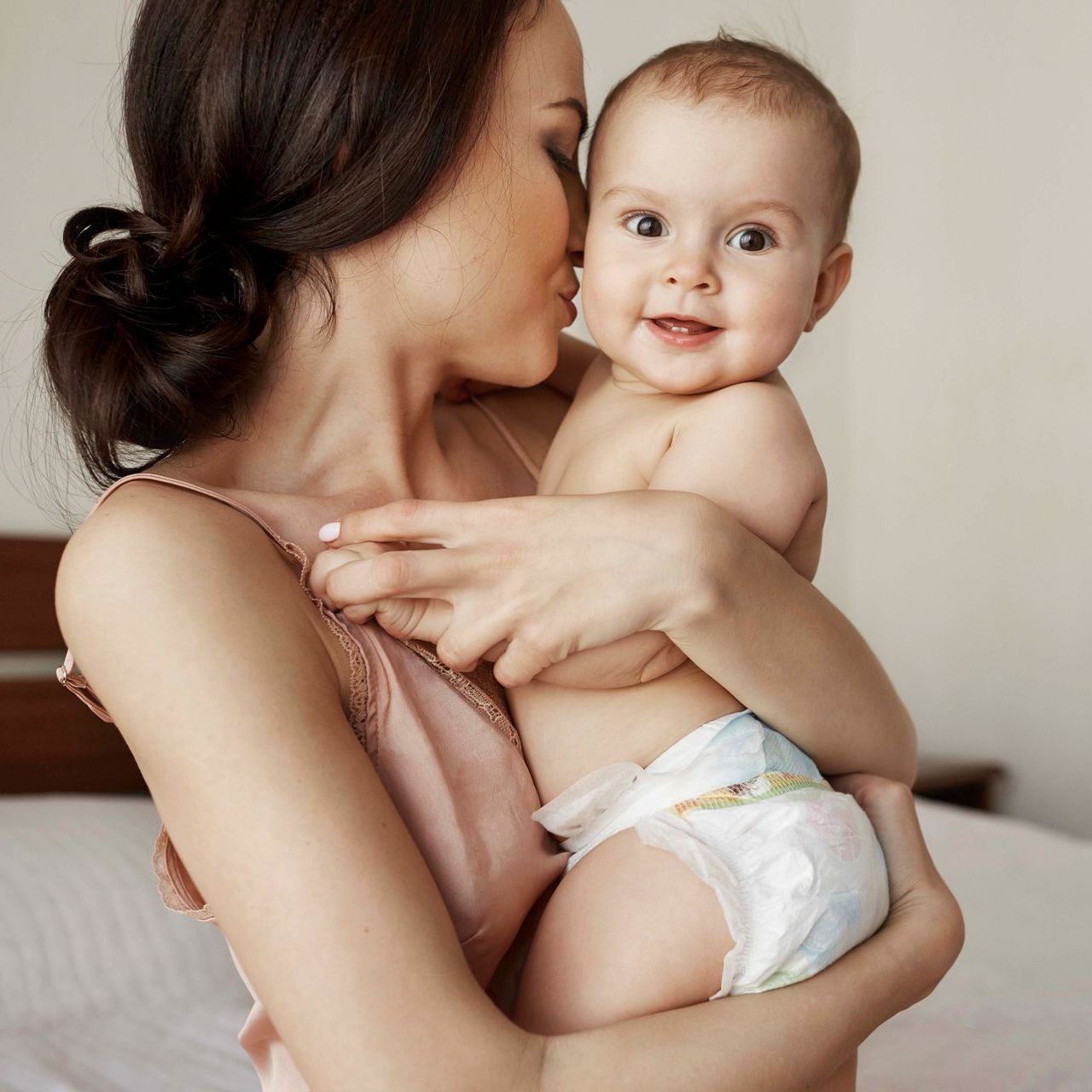 Eine Frau hält ein Baby in ihren Armen und küsst es auf die Wange.