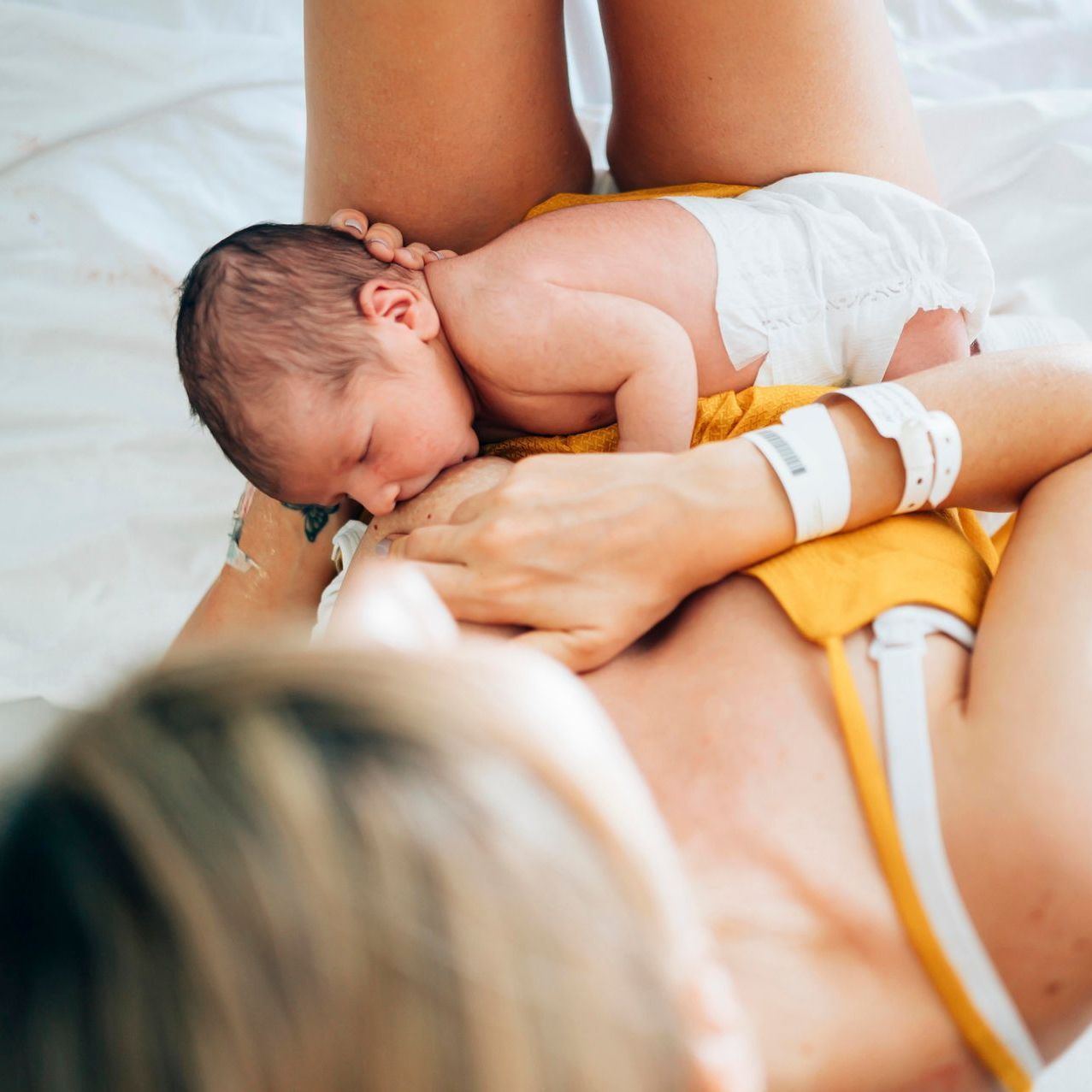 Eine Frau stillt ihr neugeborenes Baby auf einem Bett.