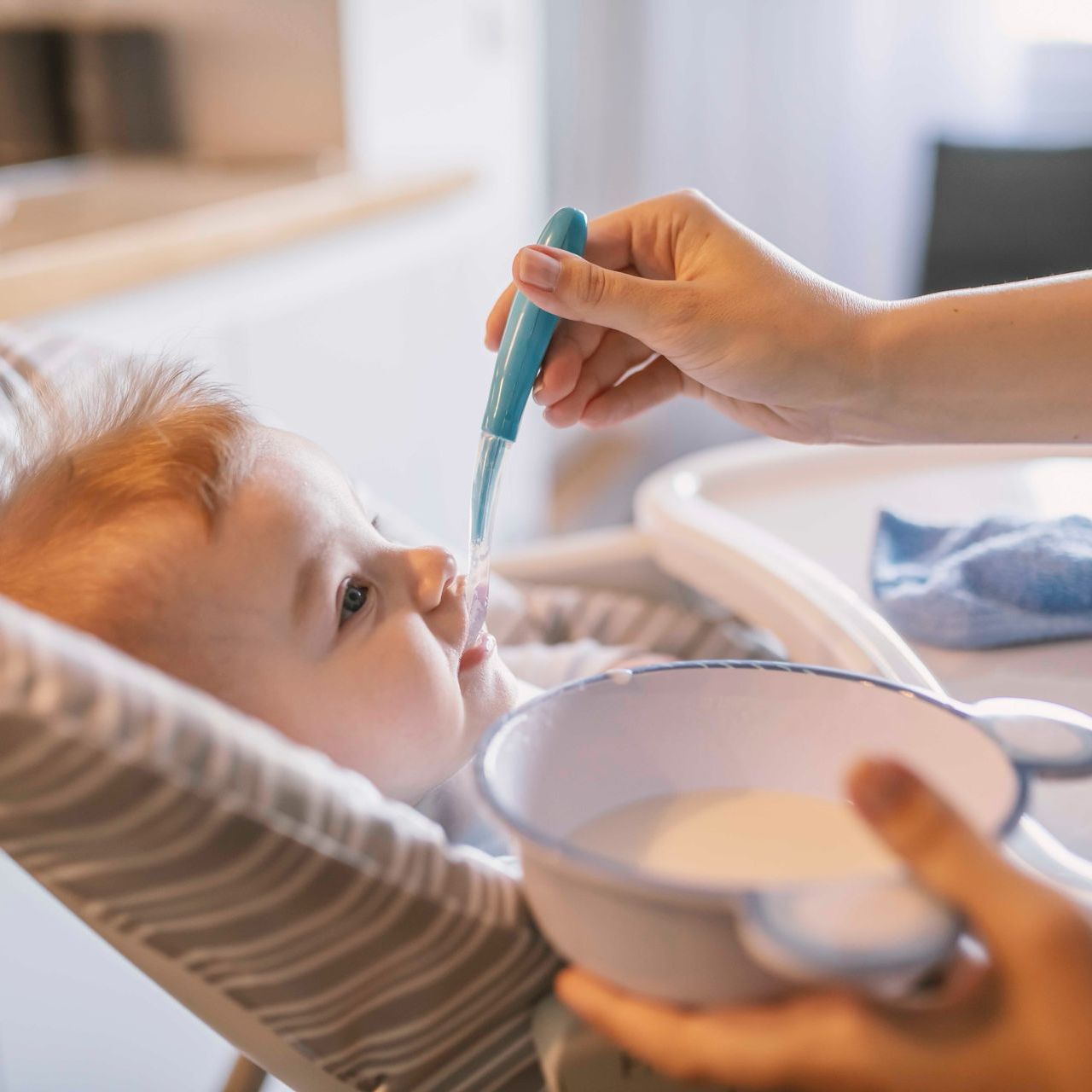 Ein Baby wird mit einem Löffel aus einer Schüssel gefüttert.