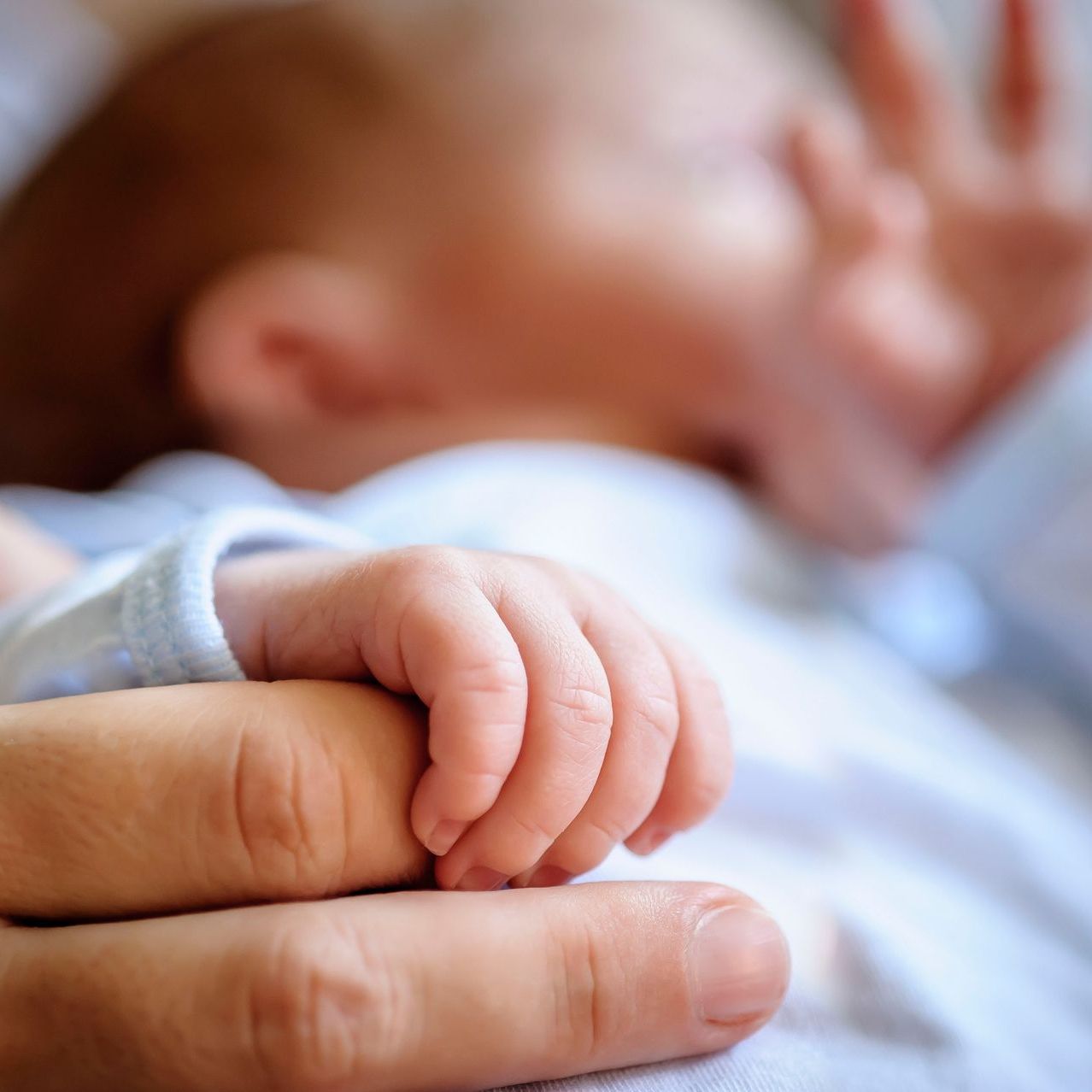 Eine Nahaufnahme einer Person, die die Hand eines Babys hält.