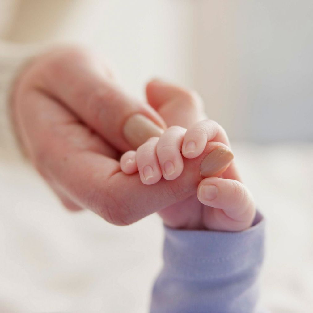 Eine Nahaufnahme einer Person, die die Hand eines Babys hält