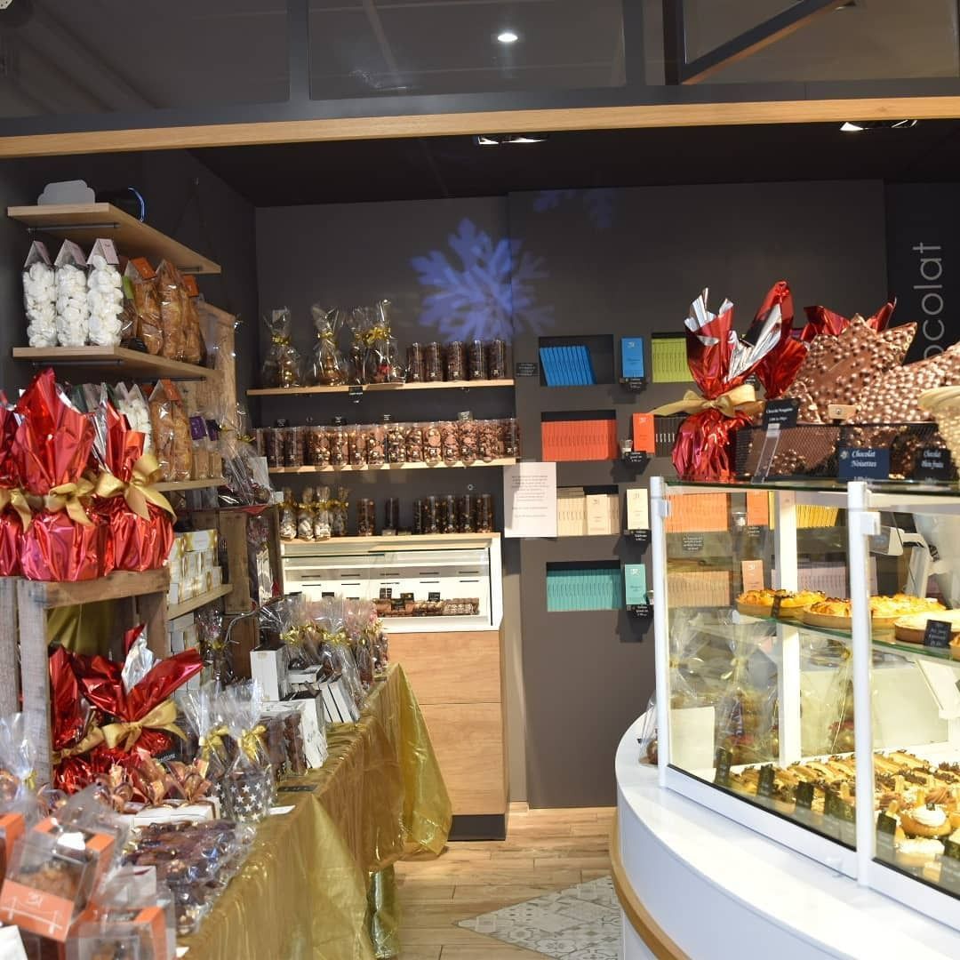 Vitrine de chocolaterie présentant diverses friandises. Étagères et vitrine remplies de bonbons.