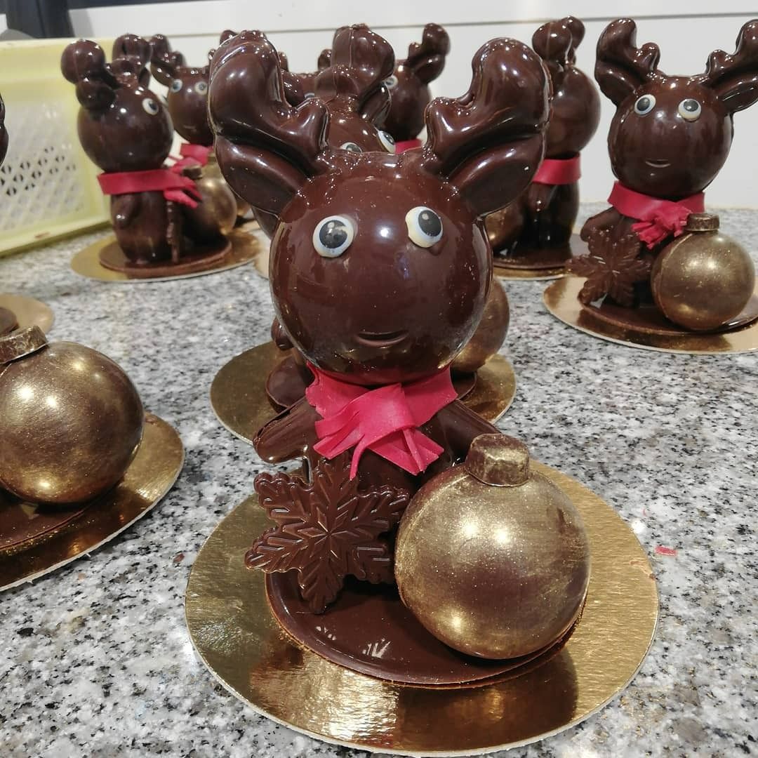 Figurines de rennes en chocolat ornées de décorations dorées sur des supports dorés.