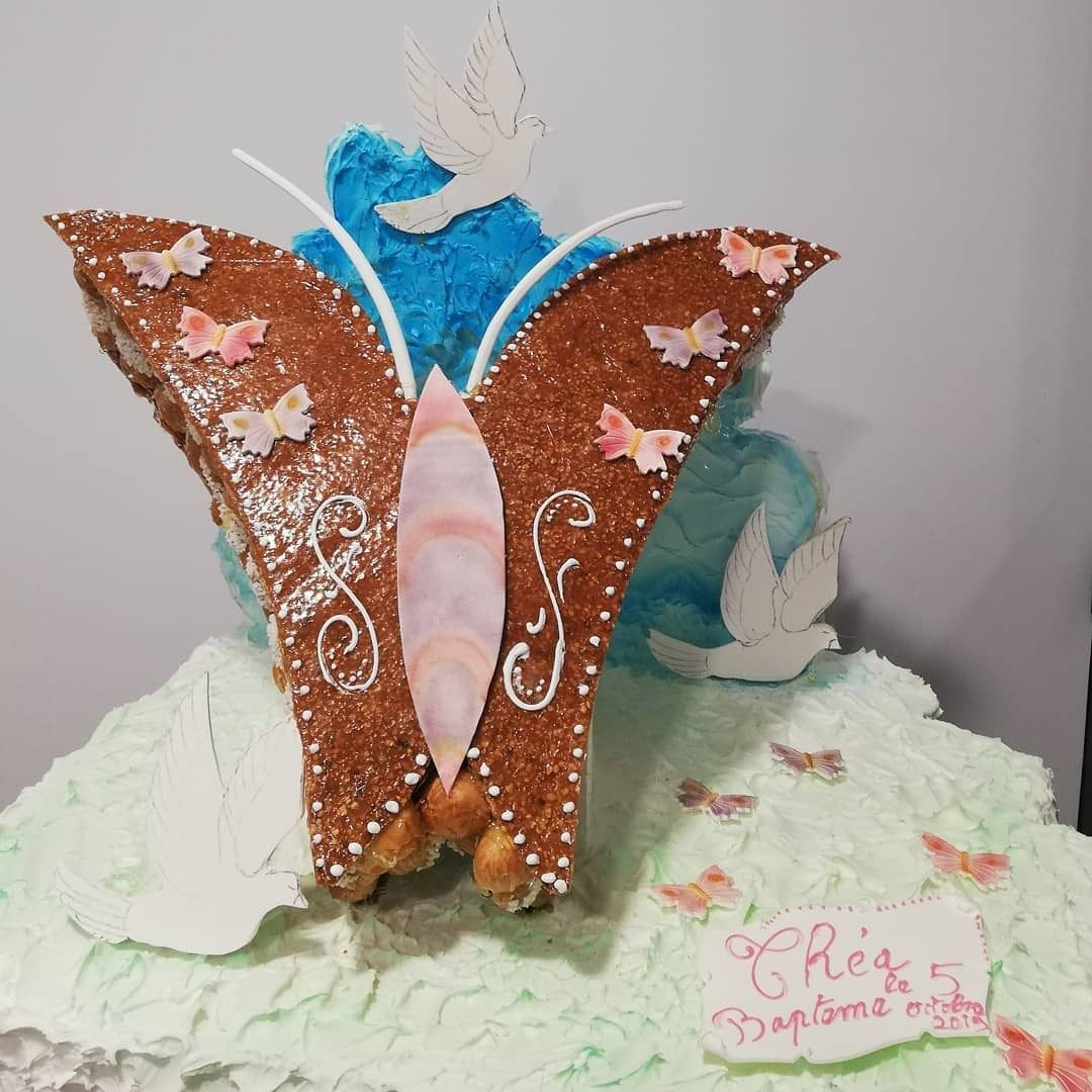 Gâteau décoré en forme de papillon, avec des colombes et un texte sur une base givrée vert clair.