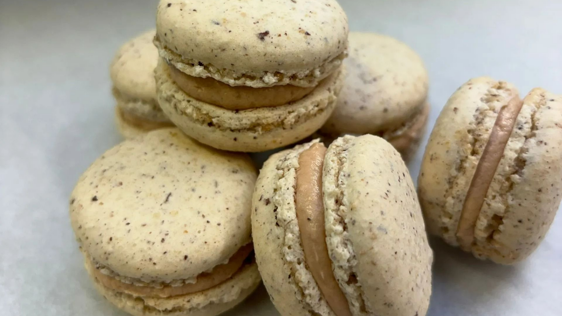 Pile de macarons beiges fourrés d'une garniture brun clair.