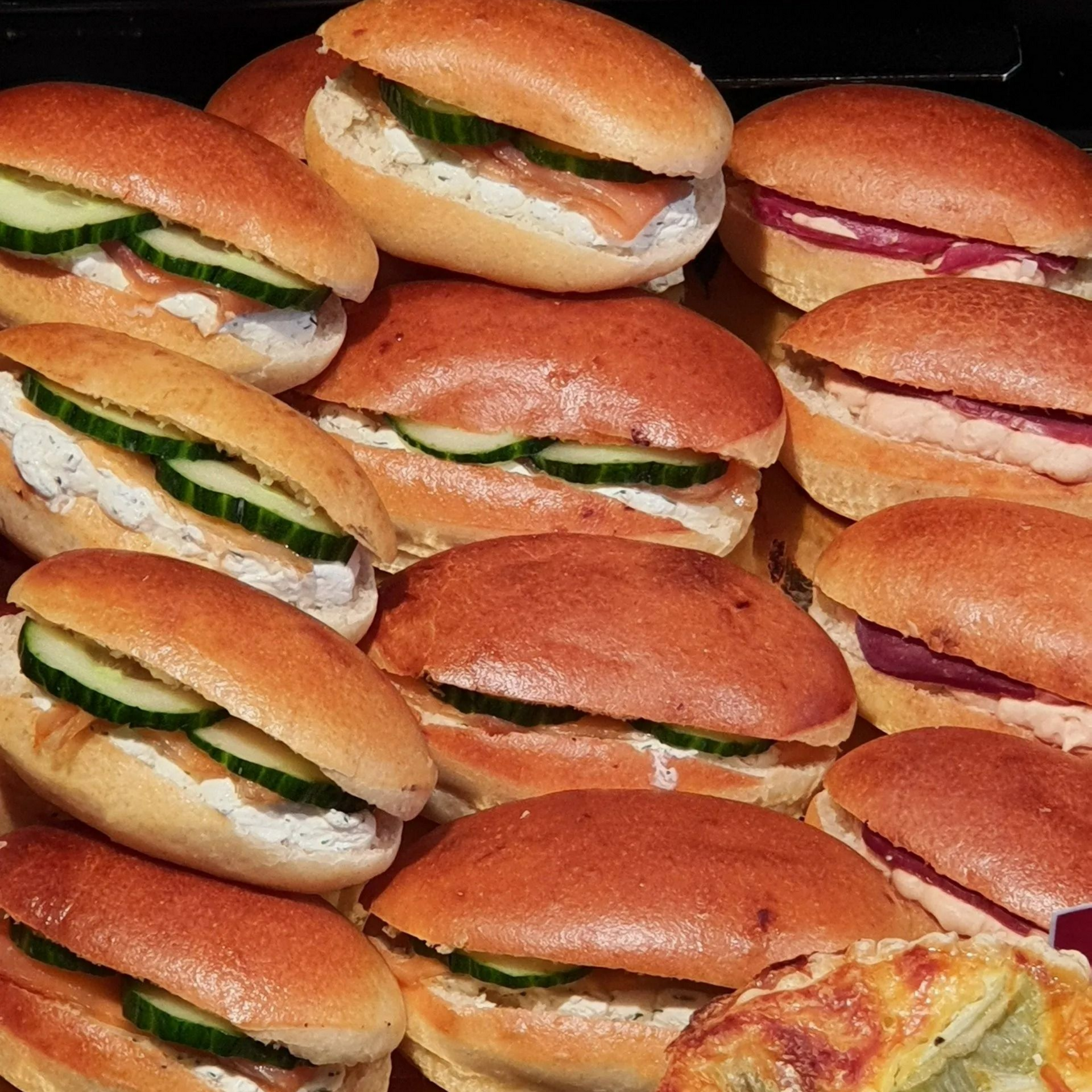 Minisandwichs aux garnitures variées, notamment concombre et saumon, présentés sur un plateau.