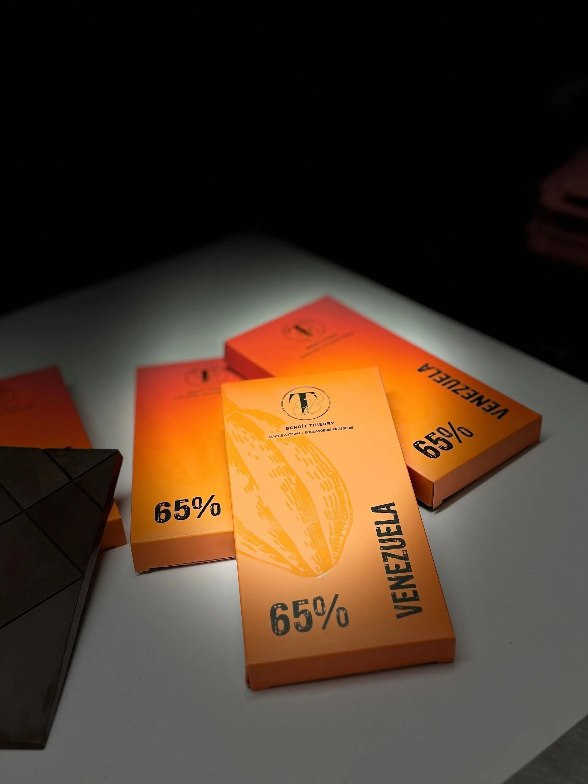 Barres de chocolat à l'emballage orange, portant l'inscription Venezuela 65 %, sur fond blanc.