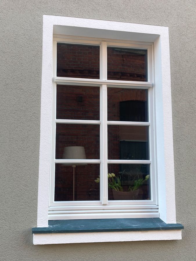Ein weißes Fenster mit einer Lampe auf der Fensterbank
