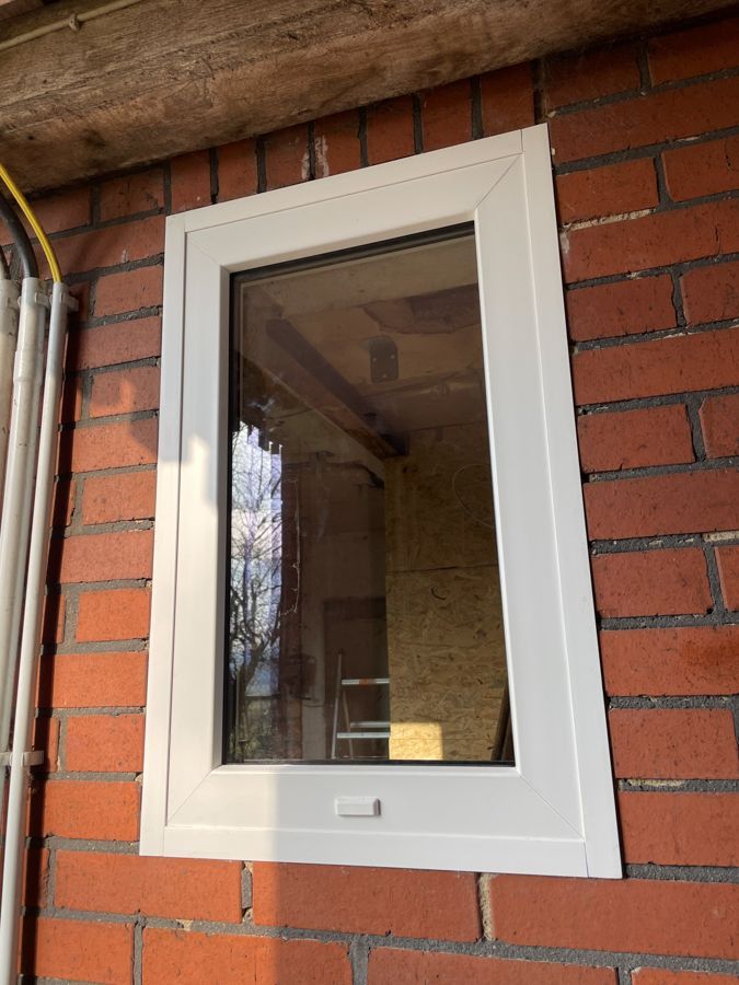 In einer Ziegelwand befindet sich ein weißes Fenster.