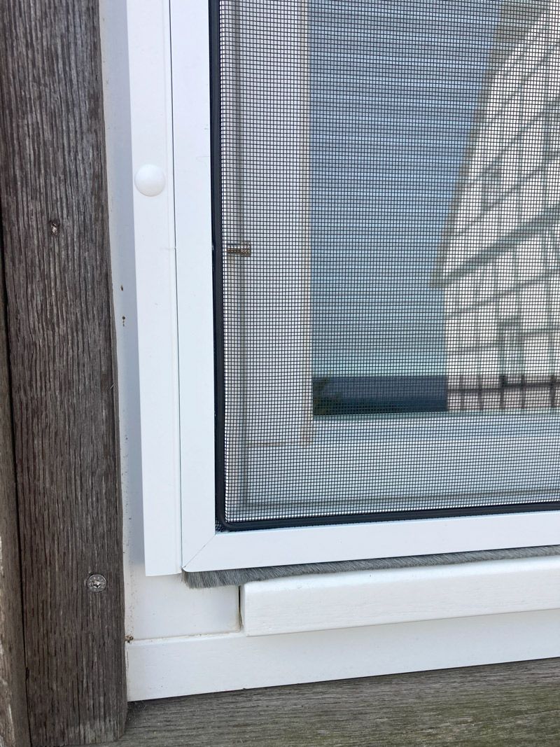 Eine Nahaufnahme eines Fensters mit einem Fliegengitter darauf.