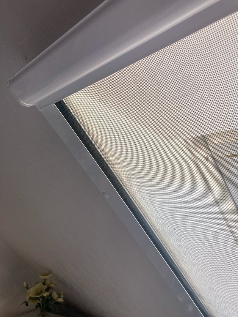 Eine Nahaufnahme eines Fensters mit einem Fliegengitter darauf.