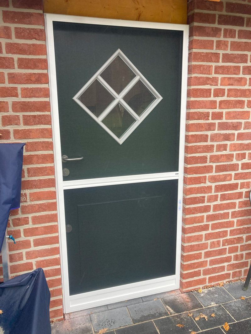 Ein Backsteingebäude mit einer Fliegengittertür mit einer Raute in der Mitte