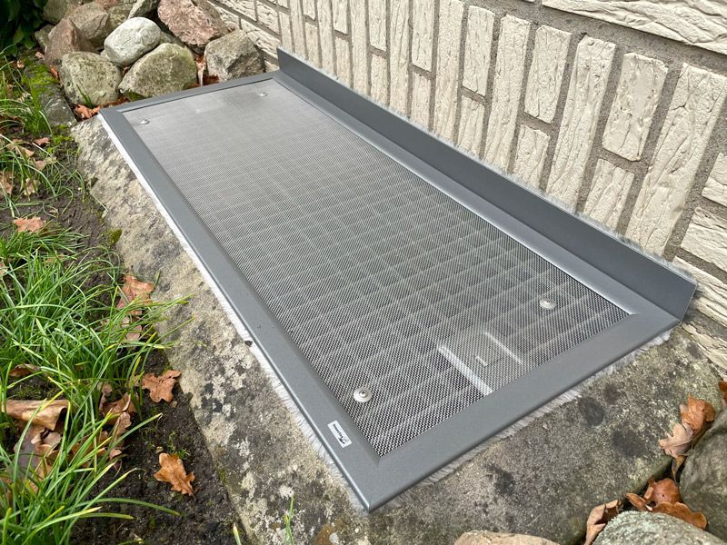 An der Seite einer Backsteinmauer hängt ein Metallgitter.