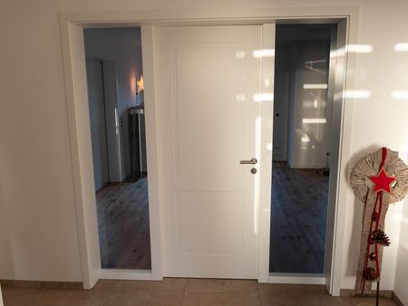 Eine weiße Tür mit einem Edelstahlgriff in einem Badezimmer.