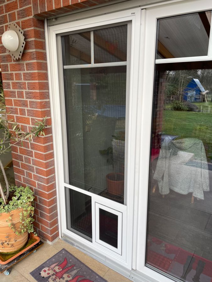 Eine weiße Glasschiebetür mit einem Fliegengitter darauf