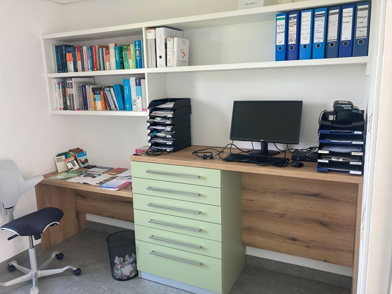 Ein Schreibtisch mit einem Computer und Ordnern darauf