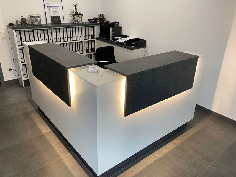 Ein Wartezimmer mit zwei Stühlen und einem Regal.