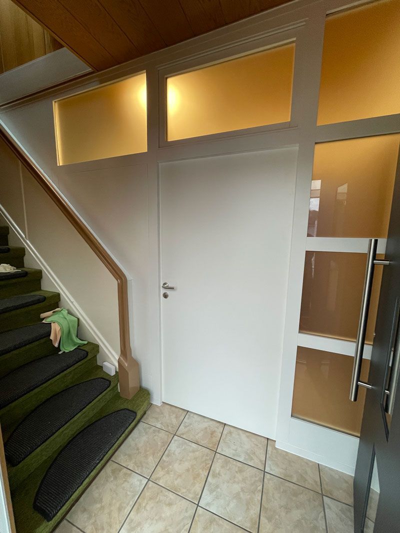 Eine Treppe mit grünen Stufen und einer weißen Tür in einem Flur.