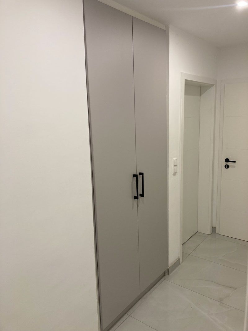 Ein Flur mit einem grauen Schrank und einer weißen Tür.
