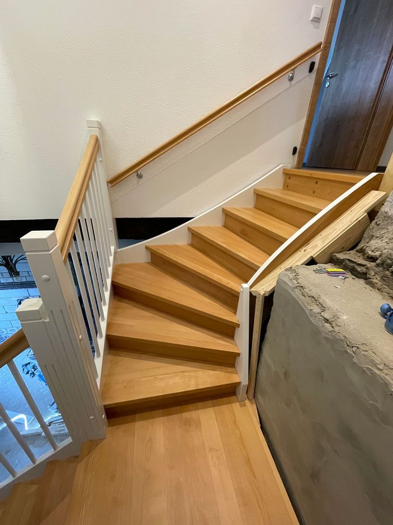 Eine Holztreppe mit weißem Geländer und Holzstufen in einem Haus.