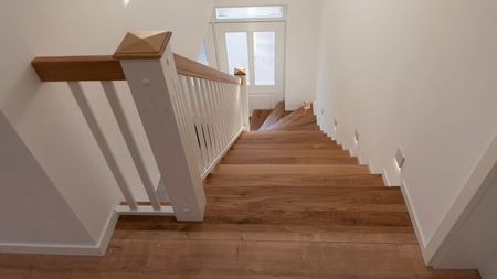 Eine Treppe mit weißem Geländer und Holzstufen