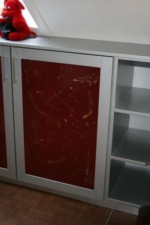Ein rotes Stofftier sitzt auf einem roten Schrank