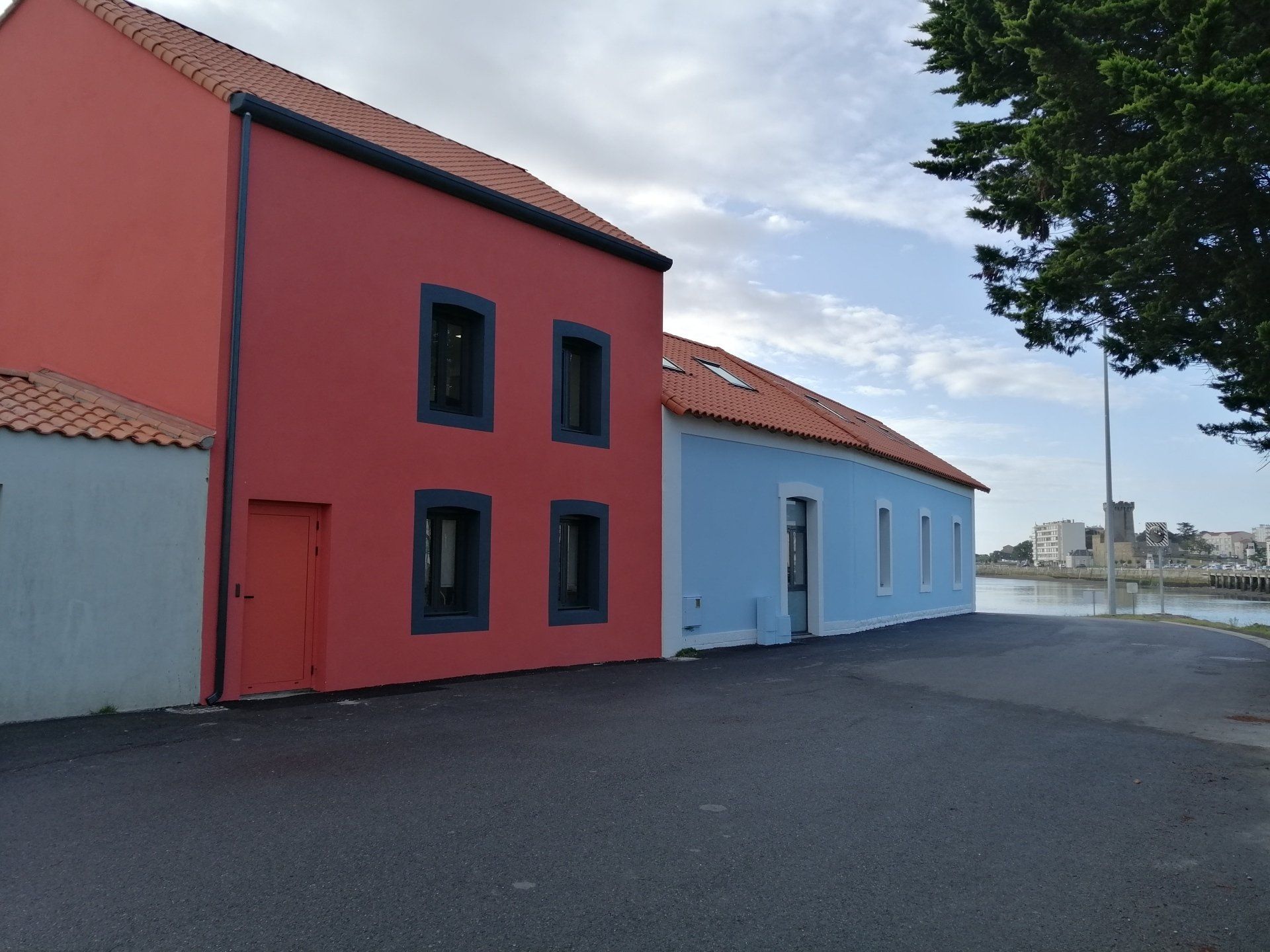 Des bâtiments rouges et bleus aux encadrements de fenêtres sombres