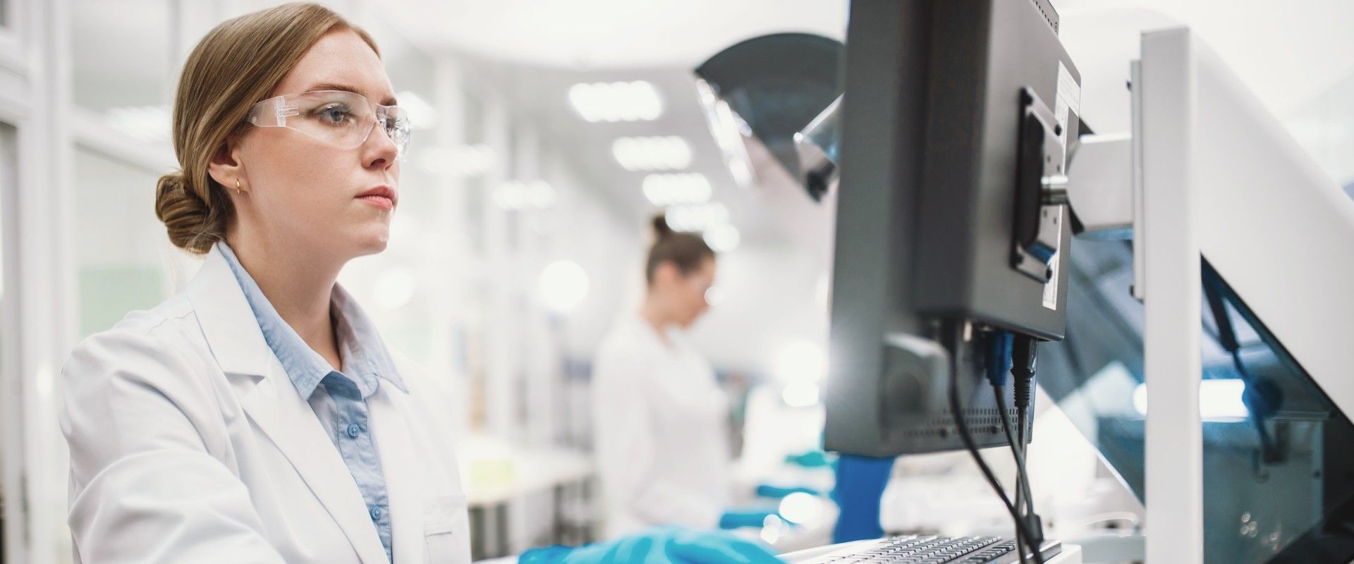 Medizinische Forscherin am PC im Laborkittel