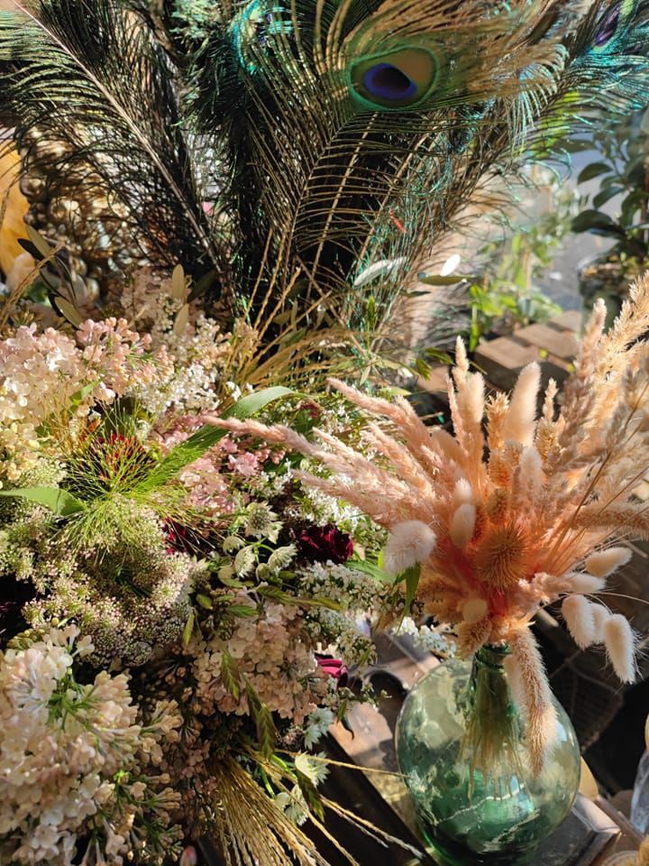 Composition florale en plumes de paon dans un vase, avec des fleurs de pampa.