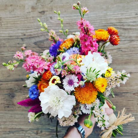 Bouquet coloré et varié, composé de fleurs mélangées disposées à la main sur une surface en bois.