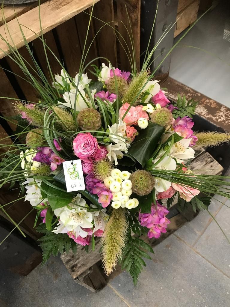 Composition florale rose, blanche et verte dans une caisse en bois.