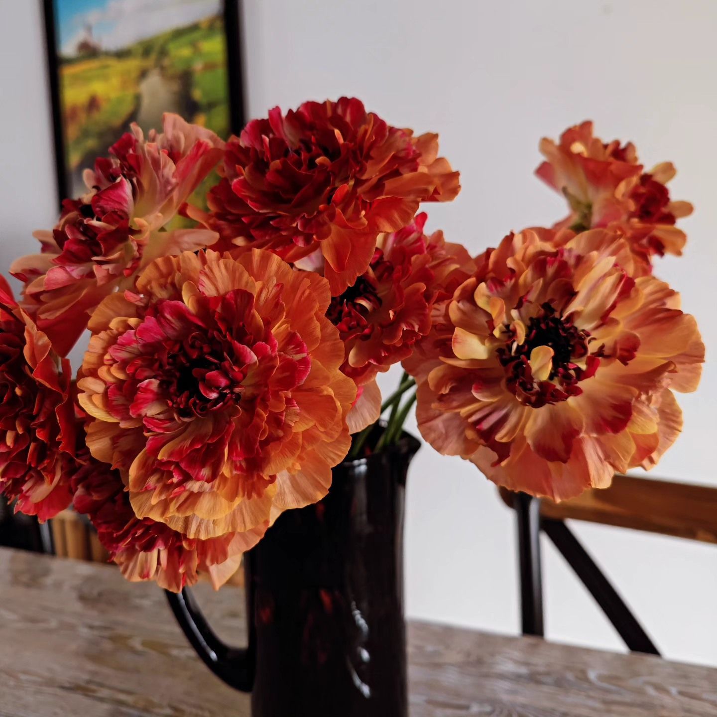 De grandes fleurs orangées dans un vase noir.