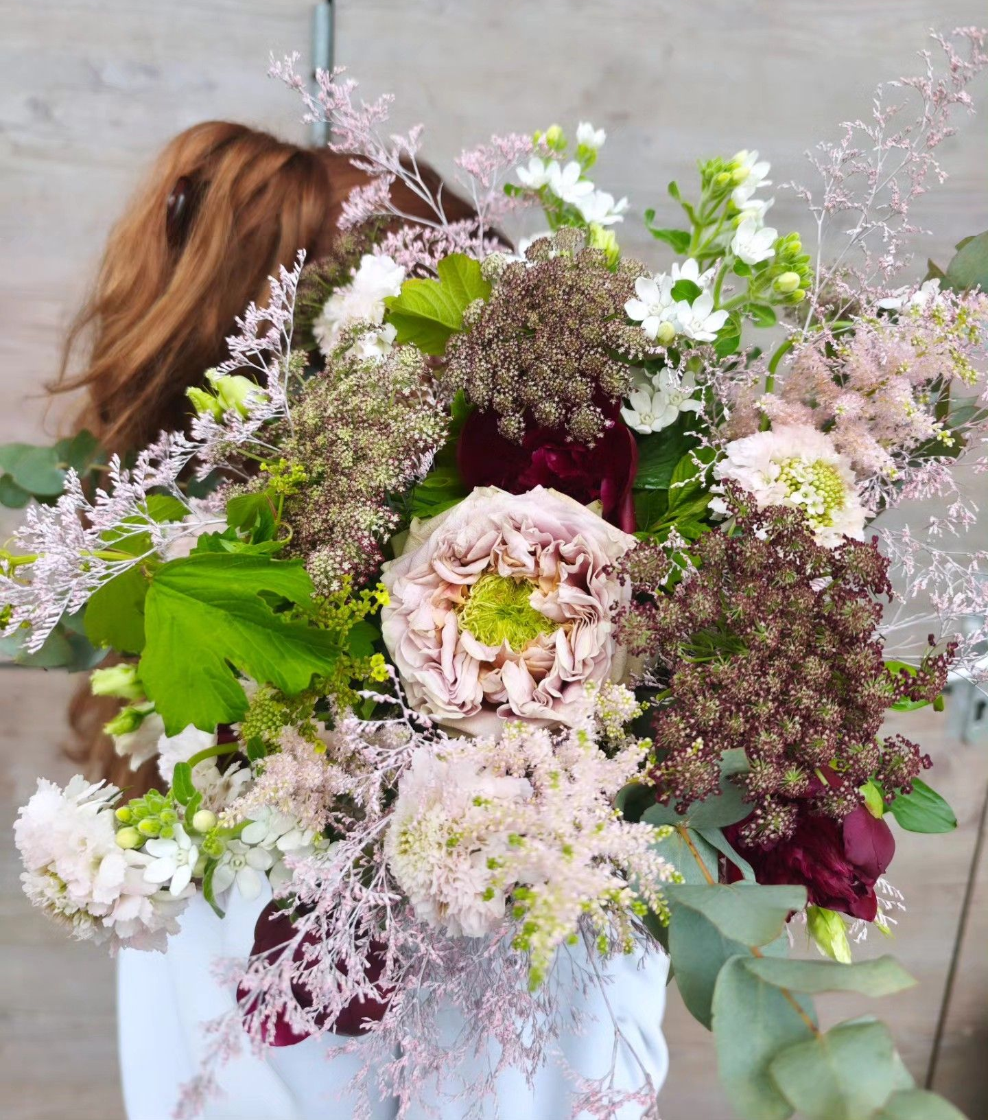 Grand bouquet de fleurs pastel avec des fleurs roses, blanches, vertes et bordeaux.