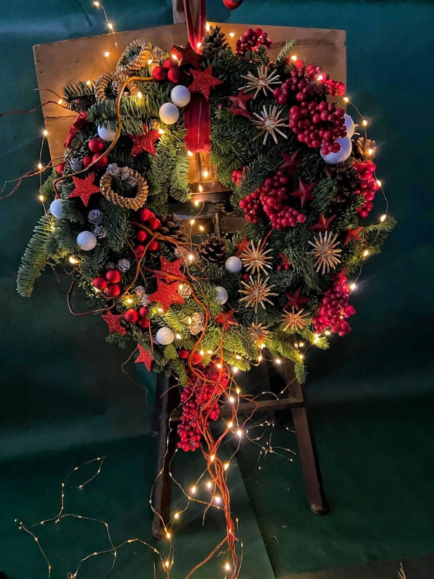 Couronne lumineuse de Noël ornée de décorations rouges, dorées et blanches.