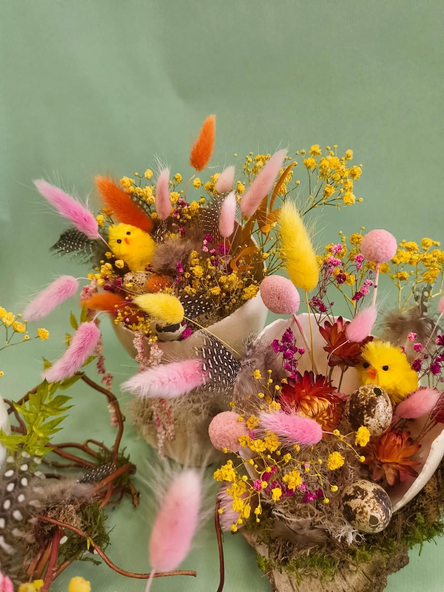 Trois bouquets de fleurs séchées aux accents roses, jaunes et orange sur un fond vert pâle.