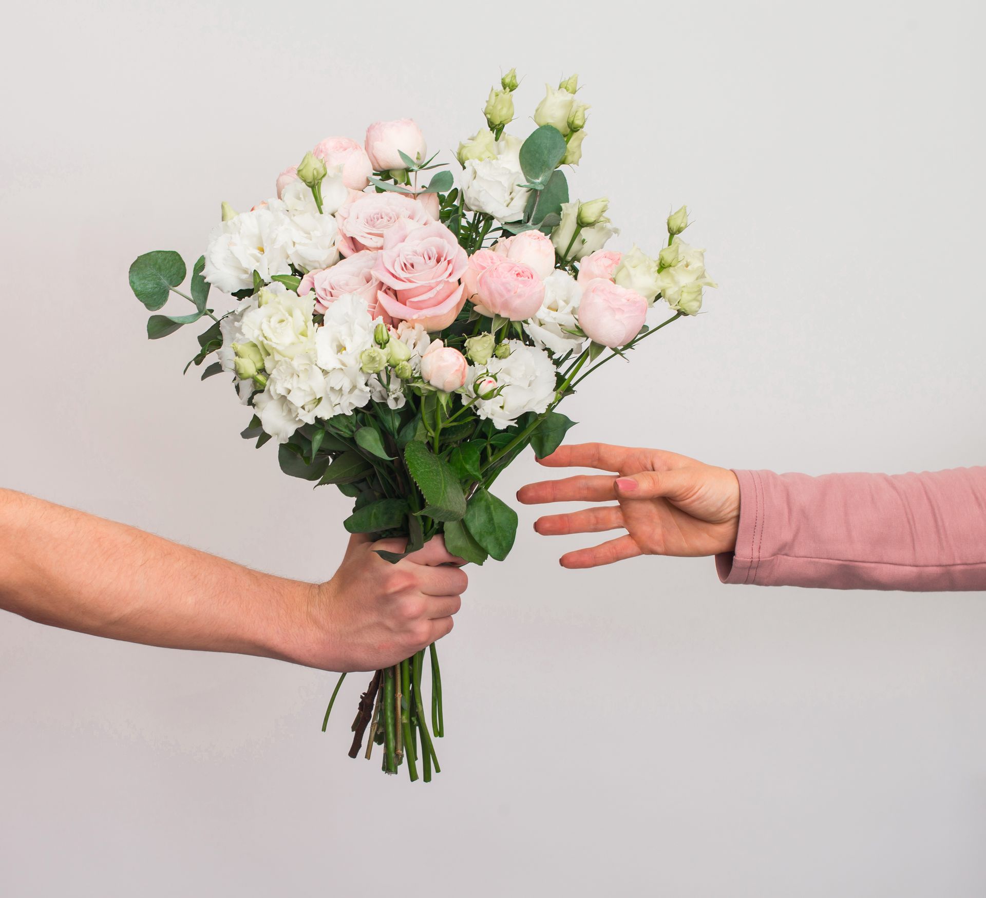Échange d'un bouquet de fleurs roses et blanches entre deux personnes.