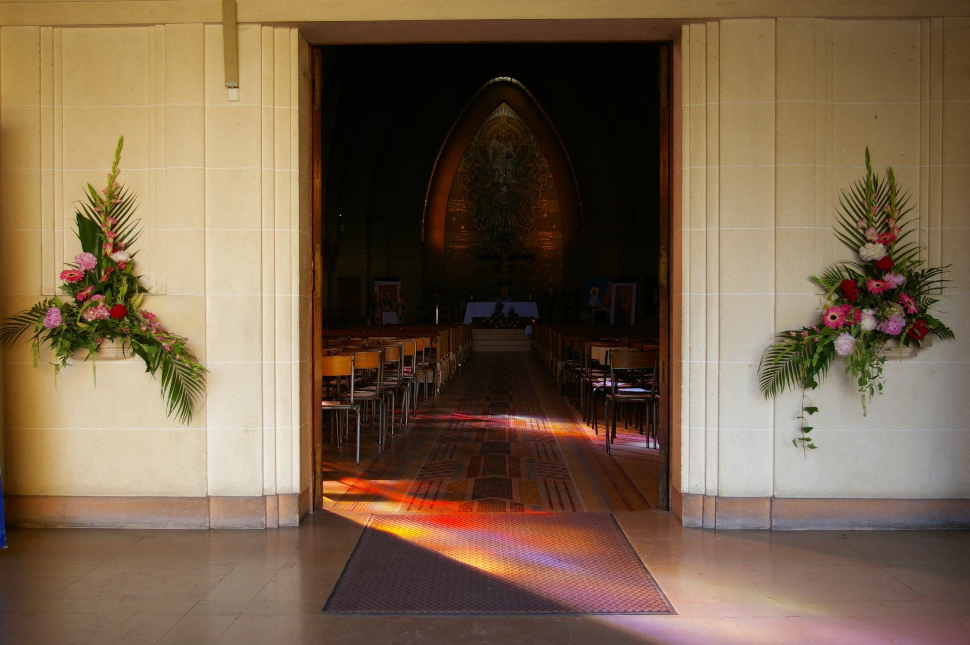 Entrée d'église bordée de fleurs avec une allée centrale menant à un autel.