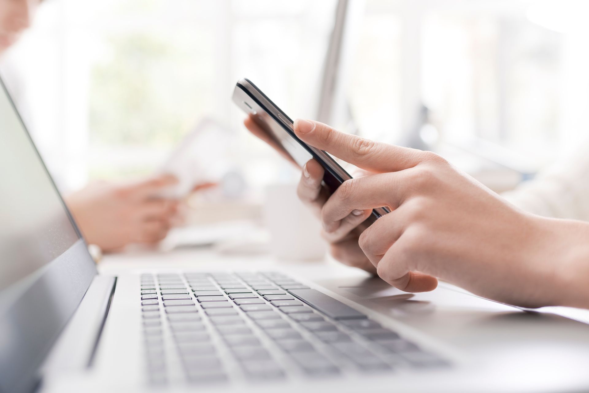 Personne devant un ordinateur qui utilise son téléphone
